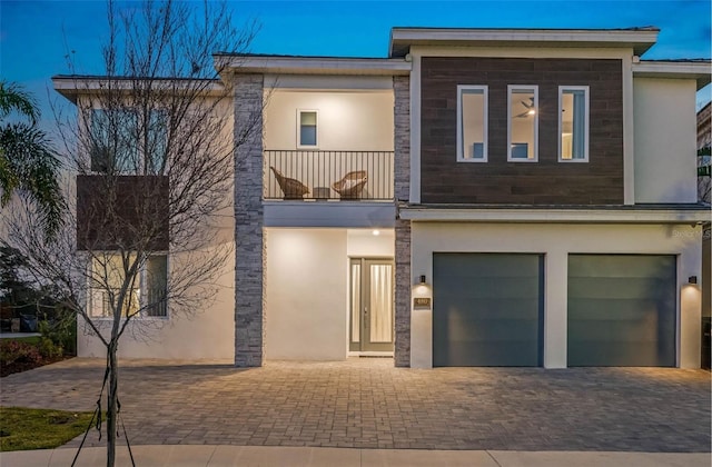 view of front of home featuring a garage, a balcony, decorative driveway, and stucco siding