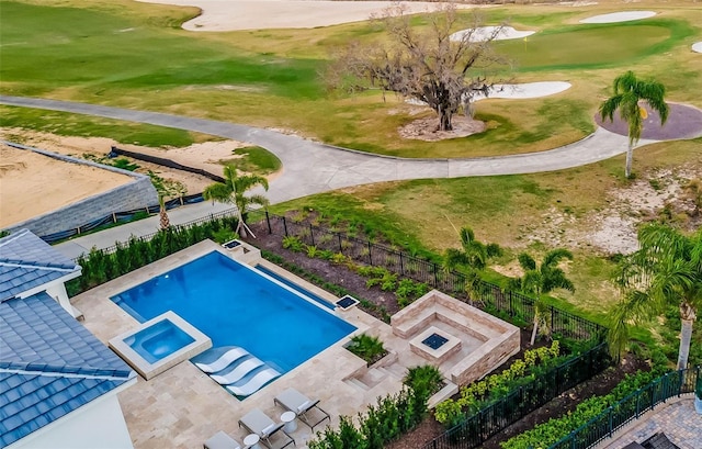 view of swimming pool with view of golf course, a pool with connected hot tub, and fence