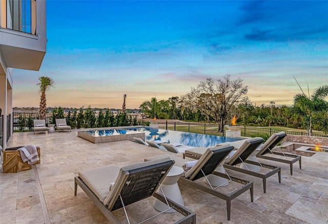 pool at dusk with a fenced in pool, a patio, fence, and a jacuzzi