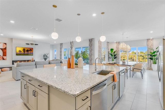 kitchen with a fireplace, a sink, visible vents, appliances with stainless steel finishes, and an island with sink