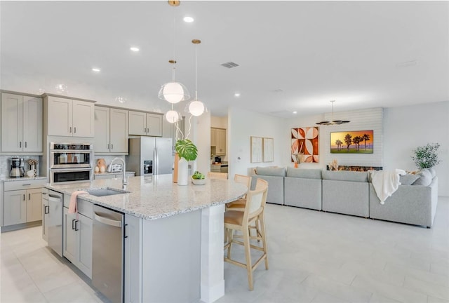 kitchen with visible vents, a large island, appliances with stainless steel finishes, gray cabinetry, and a sink