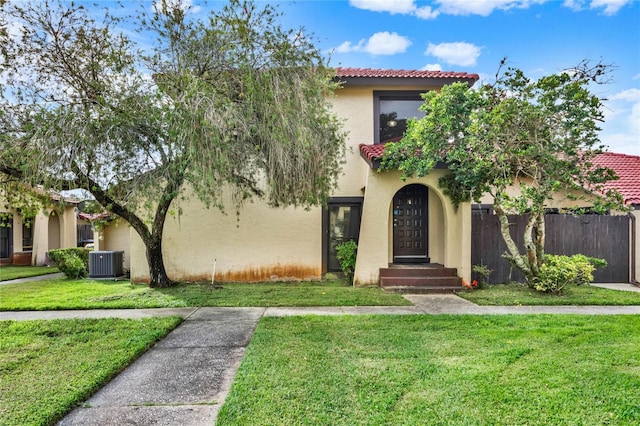 mediterranean / spanish house with a tile roof, central AC, a front lawn, and stucco siding