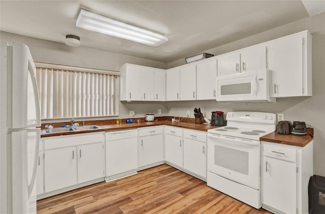 kitchen with white appliances, a sink, light wood-style flooring, and white cabinets