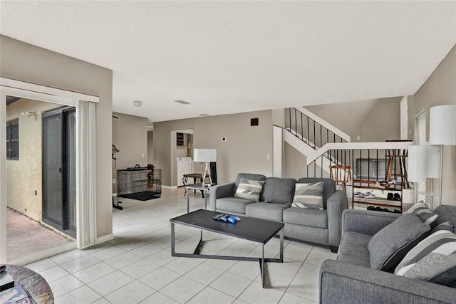 living room featuring stairs, washer / clothes dryer, a textured ceiling, and light tile patterned flooring