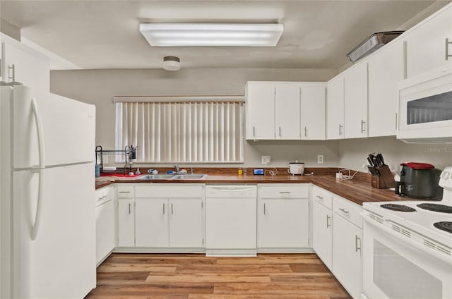 kitchen featuring white appliances, a sink, white cabinetry, light wood-style floors, and dark countertops