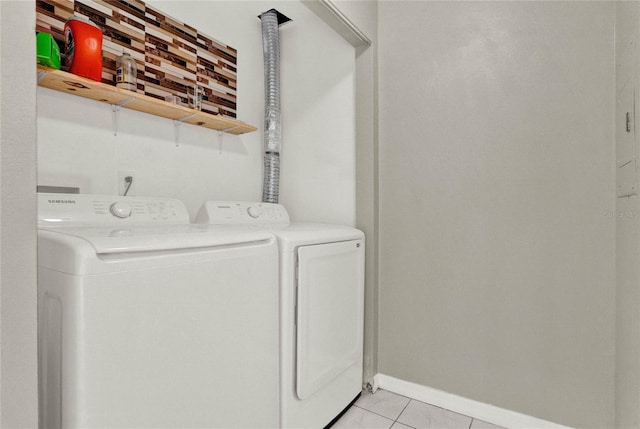 laundry area featuring light tile patterned floors, baseboards, laundry area, and washing machine and clothes dryer