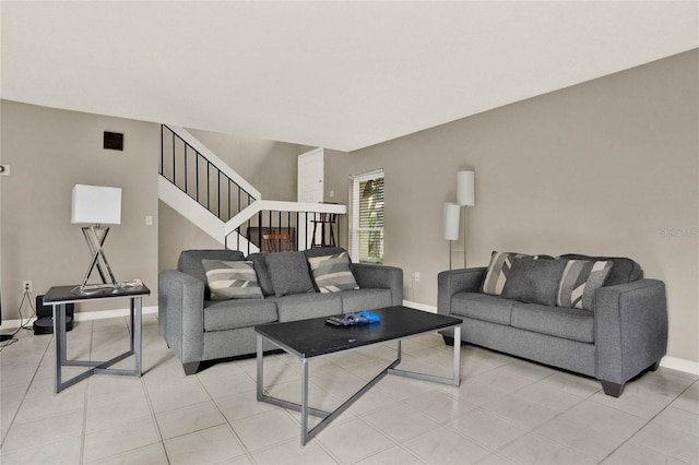 living room featuring baseboards, stairs, visible vents, and light tile patterned flooring