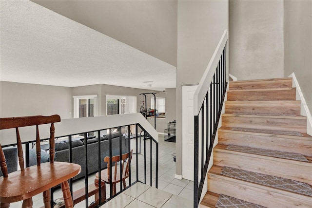 stairway with a textured ceiling and tile patterned floors