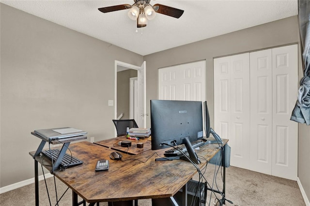 home office with light carpet, a textured ceiling, baseboards, and a ceiling fan