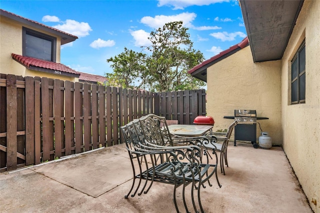 view of patio with outdoor dining space, fence, and area for grilling