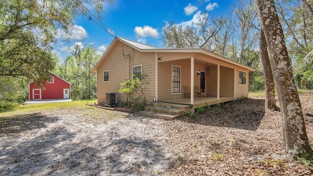 view of side of home featuring covered porch, central AC unit, and an outbuilding