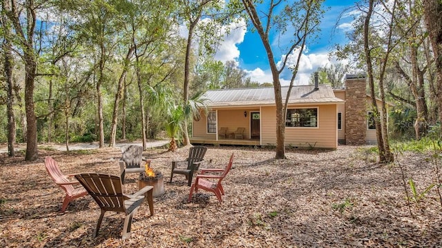 rear view of house with an outdoor fire pit, a chimney, and metal roof