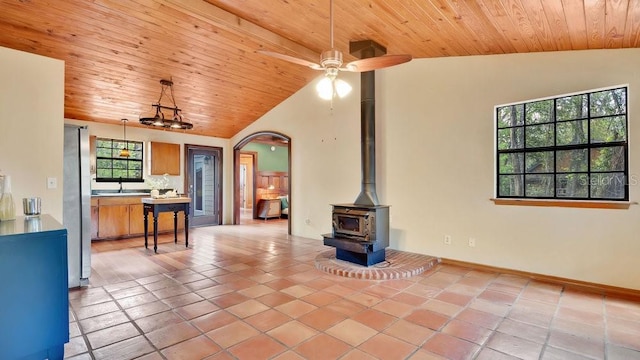 living room featuring a wood stove, wooden ceiling, arched walkways, and a wealth of natural light