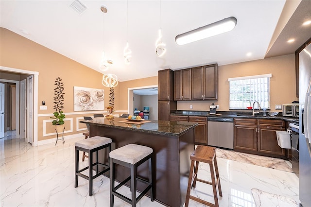 kitchen with vaulted ceiling, marble finish floor, dishwasher, and a breakfast bar area