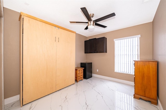 unfurnished bedroom with marble finish floor, ceiling fan, and baseboards