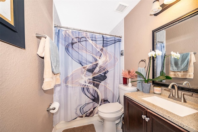 bathroom featuring toilet, a textured wall, visible vents, and vanity