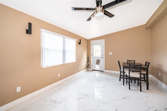 dining space with lofted ceiling, marble finish floor, a ceiling fan, and baseboards