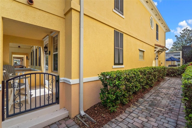 view of side of home with a gate and stucco siding