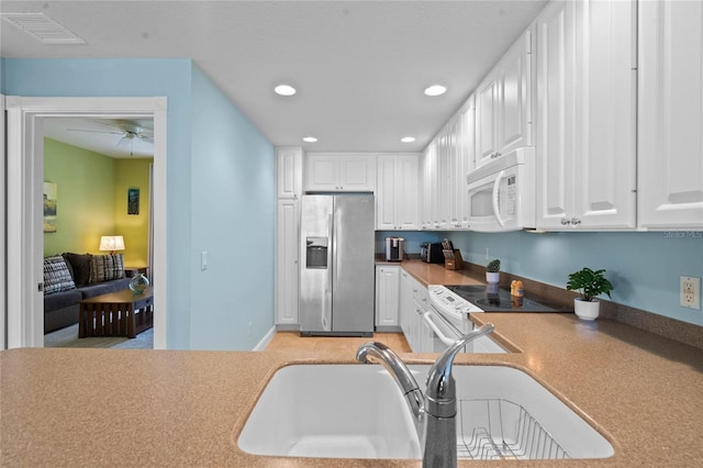 kitchen with white appliances, visible vents, a sink, and white cabinetry