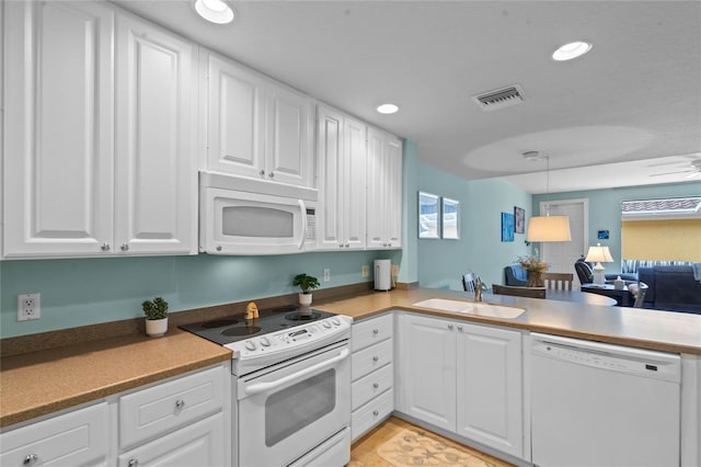 kitchen with white appliances, recessed lighting, a sink, and white cabinets