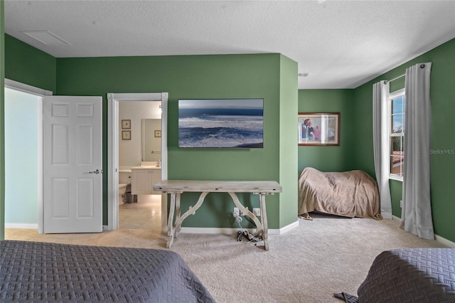 carpeted bedroom featuring a textured ceiling, ensuite bathroom, and baseboards