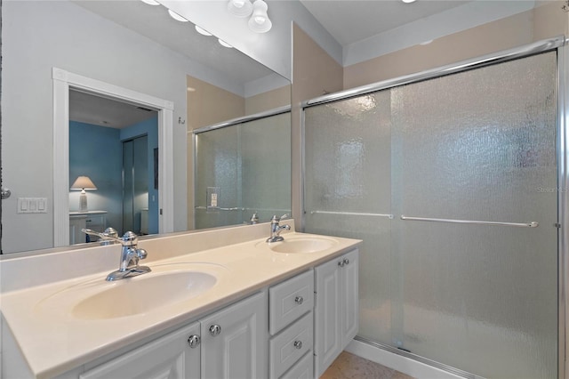 bathroom featuring double vanity, a stall shower, and a sink