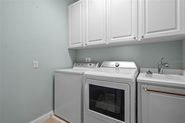 laundry area featuring washing machine and dryer, cabinet space, a sink, and baseboards