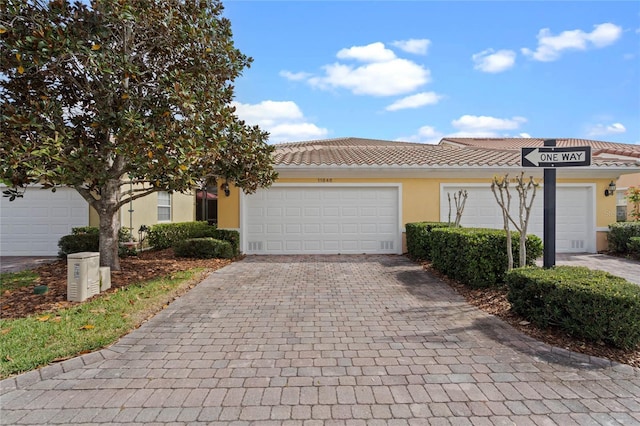 single story home with an attached garage, a tile roof, decorative driveway, and stucco siding