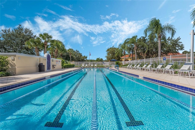 community pool with a patio area and fence