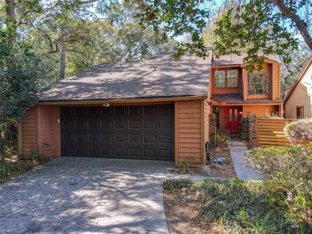 view of front of house featuring a garage, fence, decorative driveway, and roof with shingles