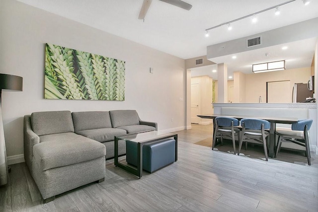 living room featuring baseboards, visible vents, ceiling fan, and wood finished floors