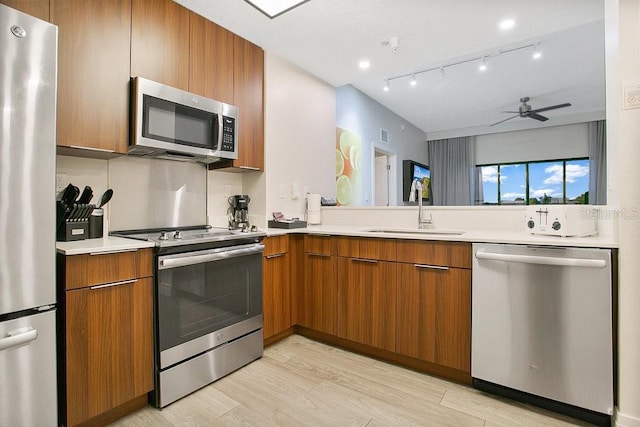 kitchen featuring appliances with stainless steel finishes, a sink, and brown cabinets