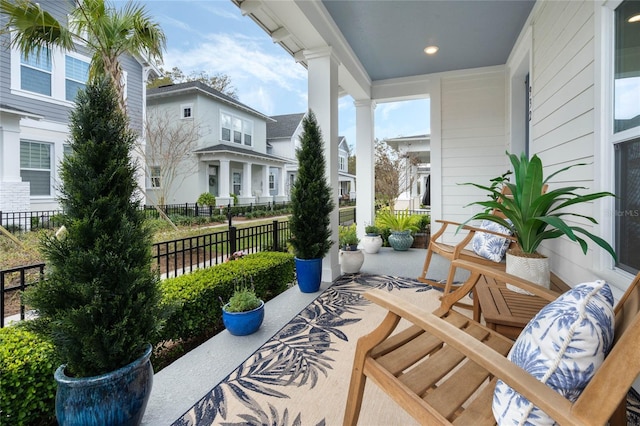 view of patio / terrace featuring covered porch, fence, and a residential view