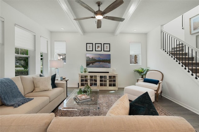 living room with a ceiling fan, wood finished floors, beamed ceiling, baseboards, and stairs