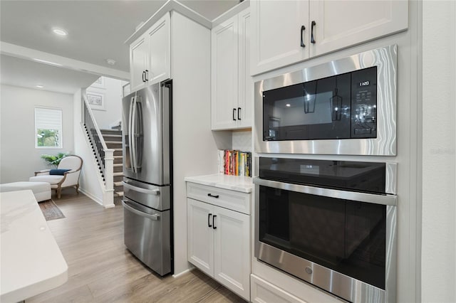 kitchen featuring recessed lighting, baseboards, white cabinets, appliances with stainless steel finishes, and light wood-type flooring