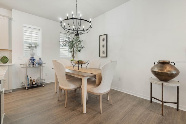 dining area featuring an inviting chandelier, baseboards, and wood finished floors