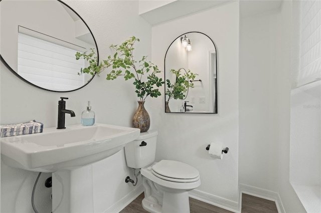 half bathroom featuring toilet, baseboards, and wood finished floors