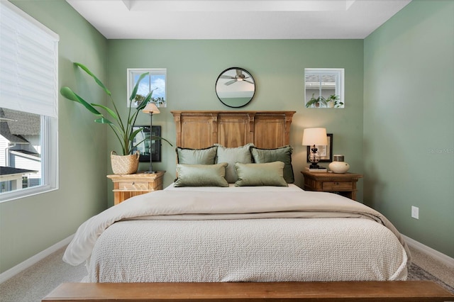 carpeted bedroom featuring multiple windows and baseboards