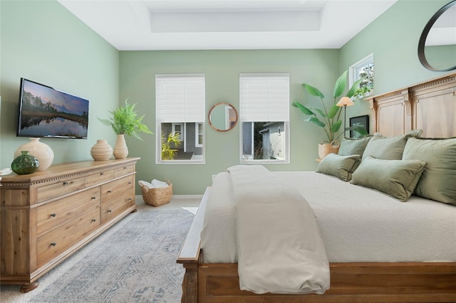 carpeted bedroom featuring a raised ceiling and baseboards