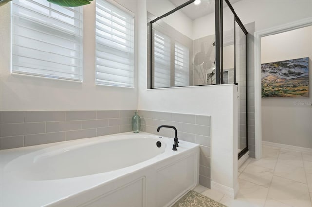 bathroom with marble finish floor, a garden tub, a shower stall, and baseboards