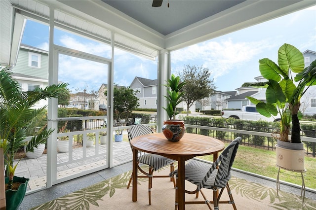 sunroom / solarium featuring ceiling fan and a residential view