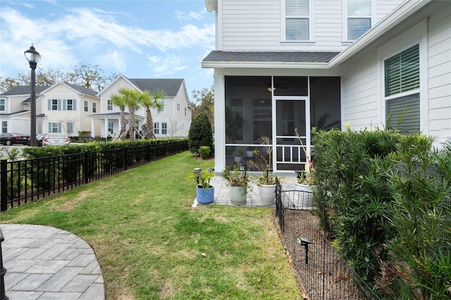 view of yard featuring a sunroom, a residential view, and fence