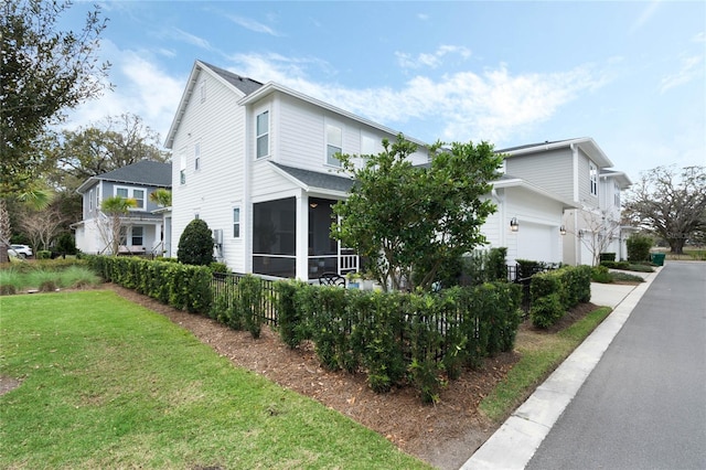 view of side of property featuring a garage, a sunroom, and a lawn