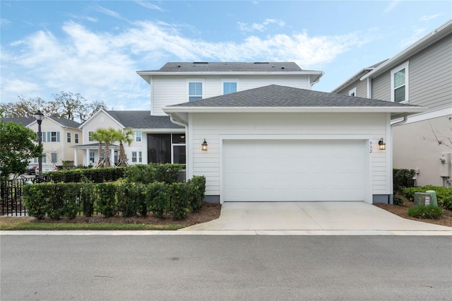 traditional-style house featuring an attached garage, driveway, fence, and roof with shingles