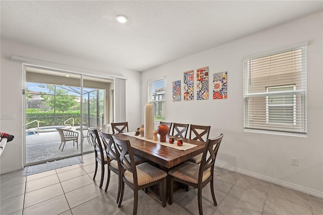 dining room featuring a textured ceiling, baseboards, and light tile patterned floors