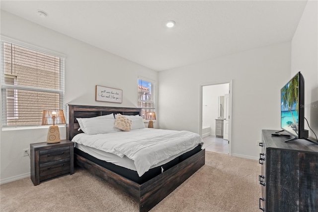 bedroom featuring baseboards, light colored carpet, and ensuite bathroom