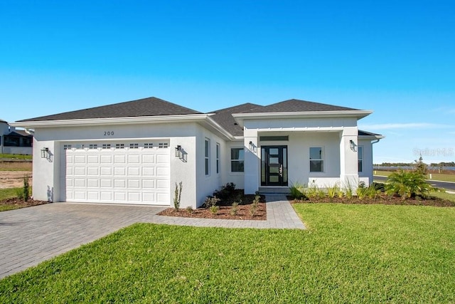 view of front of home featuring stucco siding, decorative driveway, and a front lawn