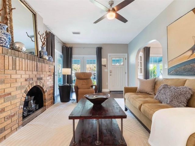 living area with a healthy amount of sunlight, ceiling fan, a fireplace, and visible vents