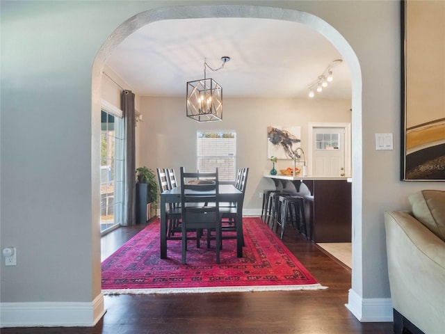 dining area with arched walkways, wood finished floors, and baseboards