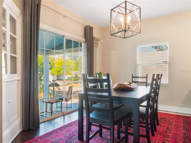 dining space featuring an inviting chandelier, wood finished floors, and baseboards